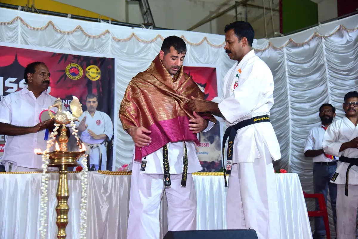 Guests honouring Renshi Pelekis beside the traditional brass lamp at the opening ceremony
