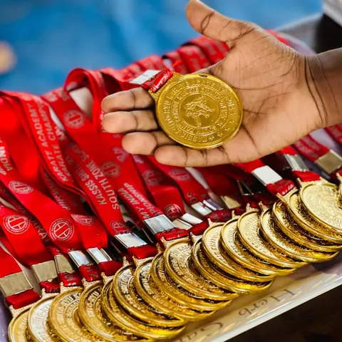 A hand holding a gold medal above rows of championship medals